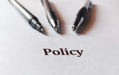Three pens pointing at the word 'policy'