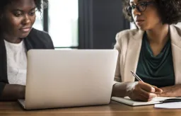 Two women sitting at laptop