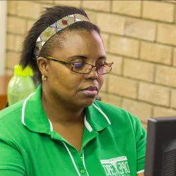 Woman wearing green and glasses reading a computer screen